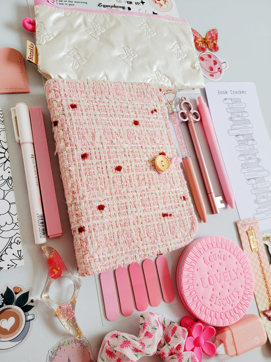 Elegant holiday gift bookish bundle flatlay featuring a pink tweed notebook cover, pastel pens, plush pencil pouch, book tracker, bookmarks, stickers, and aesthetic pink stationery. A premium Christmas gift set for book lovers, writers, and journal enthusiasts