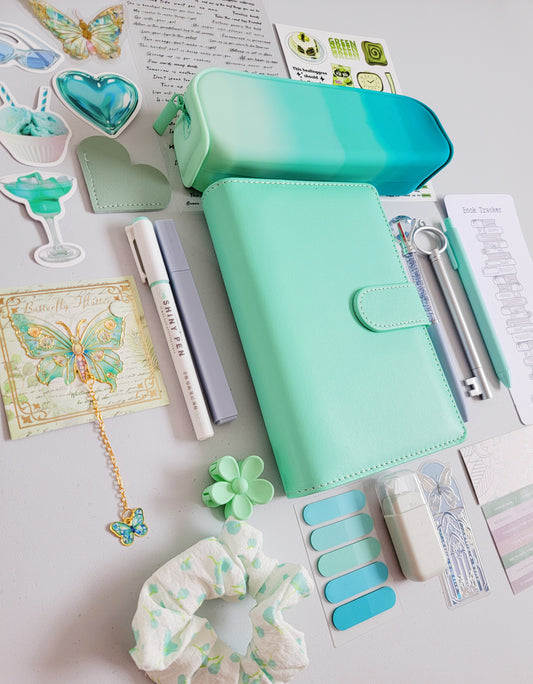 Tiffany-color bookish holiday gift bundle flatlay featuring a Tiffany blue planner cover, gradient pencil case, book tracker, pastel pens, butterfly accessories, scrunchie, stickers, tabs, and aesthetic stationery items. A cozy and elegant Christmas gift set for book lovers, journalers, and students.