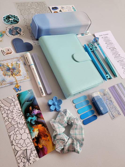 Blue/teal aesthetic bookish holiday gift bundle flatlay featuring a Tiffany blue planner cover, gradient blue pencil case, book tracker, pastel blue pens, butterfly charms, scrunchie, bookmarks, tabs, and cute stationery accessories. A cozy Christmas gift set for book lovers, journalers, and students.