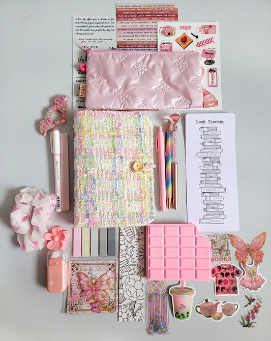 Christmas Bookish Bundle flatlay featuring pastel stationery gifts: A6 tweed notebook, pink pencil case, kawaii pens, book tracker, sticky notes, scrunchie, acrylic bookmarks, butterfly stickers, and planner accessories. Aesthetic pastel holiday gift set, perfect for readers, journaling lovers, stocking stuffers, and Secret Santa Christmas presents
