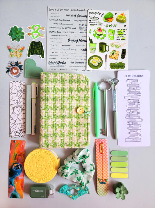 Green aesthetic bookish holiday gift bundle flatlay featuring a green tweed notebook cover, pastel green pens, book tracker, stickers, bookmarks, scrunchie, page tabs, pencil sharpener, and cute stationery accessories. A cozy Christmas gift set for book lovers, students, and journaling enthusiasts.
