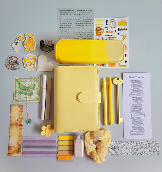Yellow aesthetic bookish holiday gift bundle flatlay featuring a pastel yellow planner cover, yellow gradient pencil case, book tracker, yellow pens, bookmarks, scrunchie, stickers, tabs, and cute stationery accessories. A bright and cheerful Christmas gift set for book lovers, students, and journaling enthusiasts.