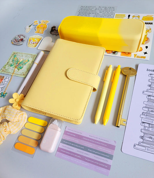 Yellow aesthetic bookish holiday gift bundle flatlay featuring a pastel yellow planner cover, yellow gradient pencil case, book tracker, yellow pens, bookmarks, scrunchie, stickers, tabs, and cute stationery accessories. A bright and cheerful Christmas gift set for book lovers, students, and journaling enthusiasts.