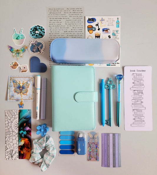 Blue/teal aesthetic bookish holiday gift bundle flatlay featuring a Tiffany blue planner cover, gradient blue pencil case, book tracker, pastel blue pens, butterfly charms, scrunchie, bookmarks, tabs, and cute stationery accessories. A cozy Christmas gift set for book lovers, journalers, and students.