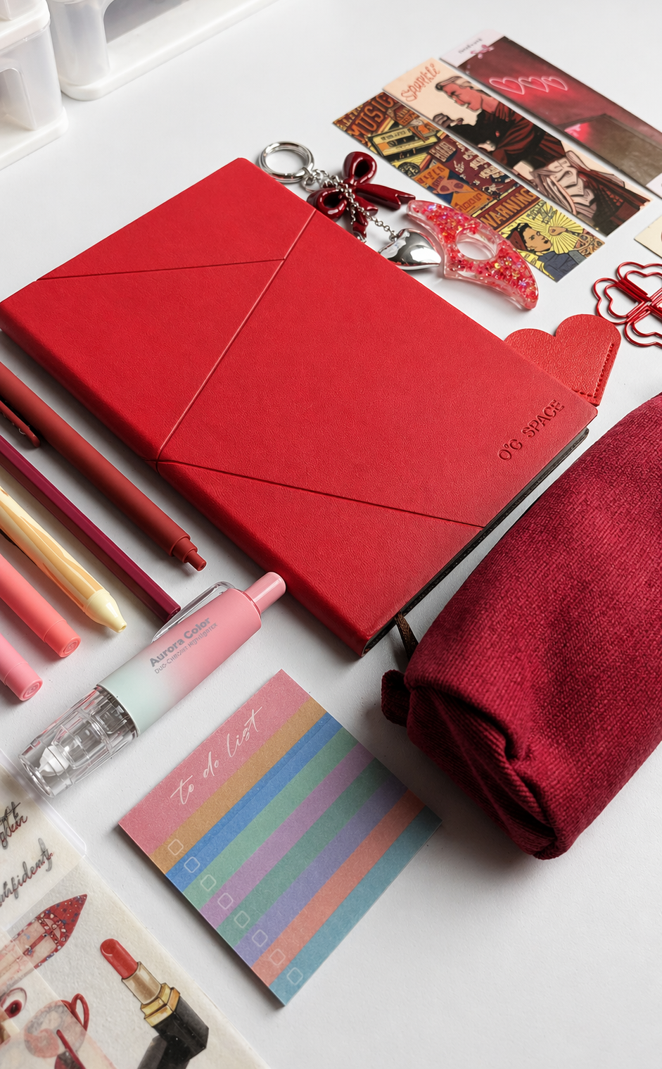 Red notebook with stationery items on a white surface